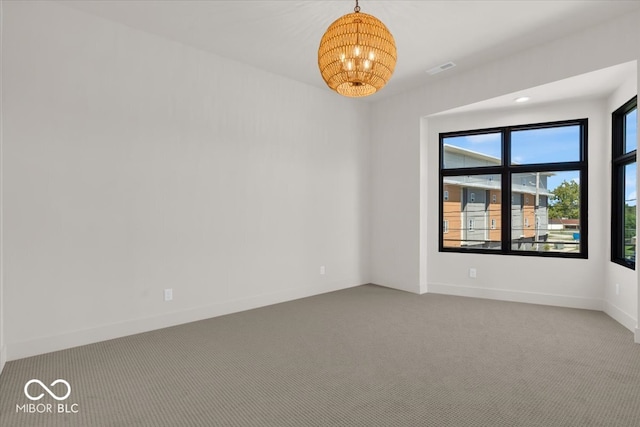 carpeted spare room featuring an inviting chandelier