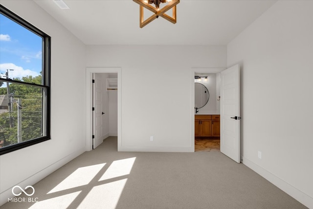 unfurnished bedroom featuring a walk in closet, light colored carpet, connected bathroom, and a closet