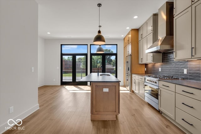 kitchen featuring light hardwood / wood-style flooring, an island with sink, premium appliances, and wall chimney range hood