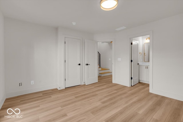 unfurnished bedroom featuring light wood-type flooring and ensuite bathroom