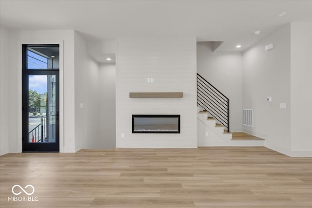 unfurnished living room with a large fireplace and light hardwood / wood-style floors