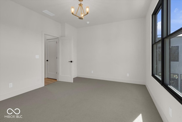 empty room featuring a notable chandelier and carpet floors