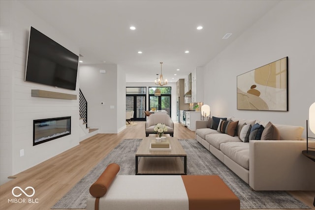 living room featuring light hardwood / wood-style flooring, an inviting chandelier, and a large fireplace