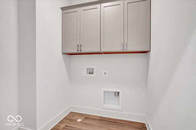 clothes washing area with washer hookup, cabinets, electric dryer hookup, and light wood-type flooring