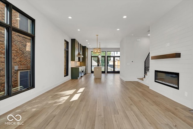 unfurnished living room featuring light hardwood / wood-style flooring, an inviting chandelier, and a fireplace