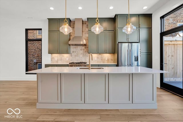 kitchen featuring light hardwood / wood-style floors, stainless steel appliances, sink, and a kitchen island with sink