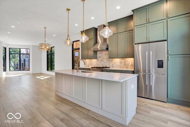 kitchen with sink, decorative light fixtures, appliances with stainless steel finishes, and light hardwood / wood-style floors