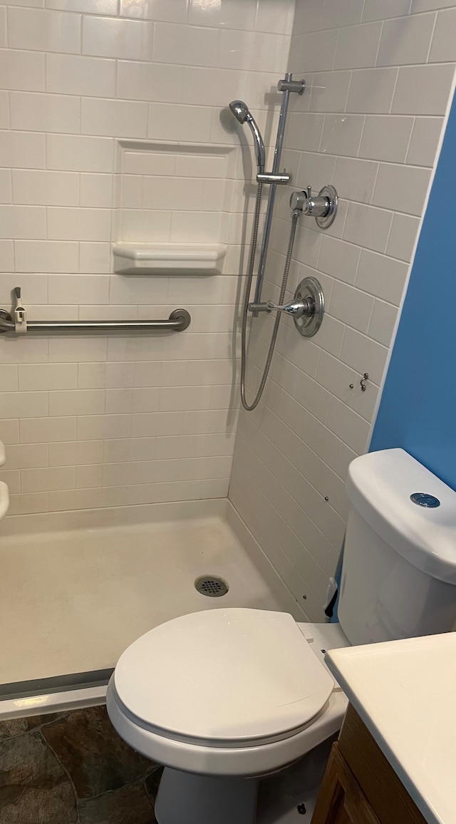 bathroom featuring vanity, tile floors, toilet, and tiled shower