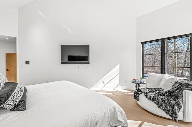 bedroom with light wood-type flooring and high vaulted ceiling