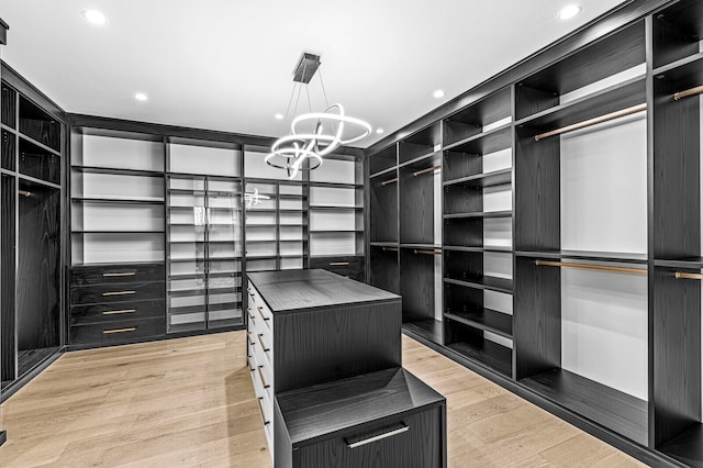 walk in closet featuring an inviting chandelier and light hardwood / wood-style floors