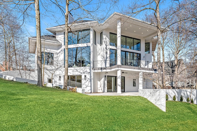 rear view of house with a balcony and a lawn