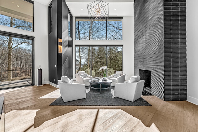 interior space with a towering ceiling, a notable chandelier, light wood-type flooring, and a fireplace