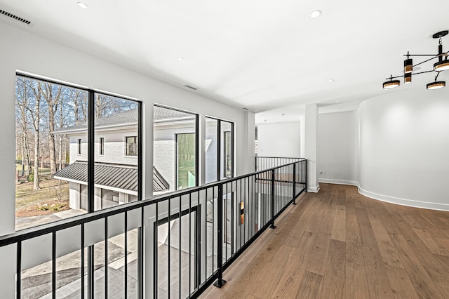 corridor with an inviting chandelier and hardwood / wood-style flooring