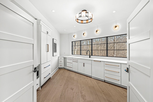 kitchen with white cabinets, light hardwood / wood-style flooring, and sink