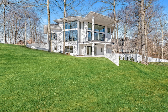 rear view of house with a balcony and a lawn