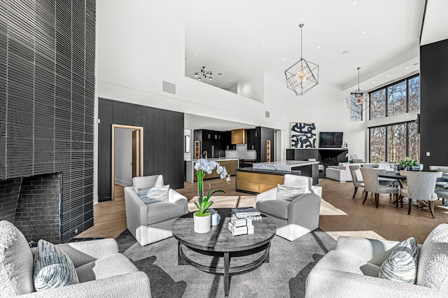 living room with a chandelier, a high ceiling, and light hardwood / wood-style floors