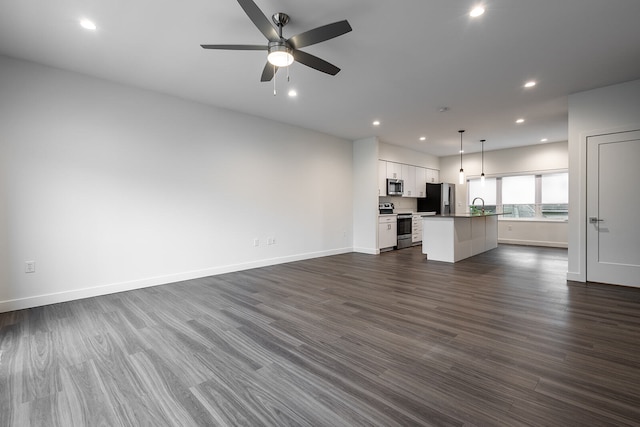 unfurnished living room featuring ceiling fan, sink, and dark hardwood / wood-style flooring