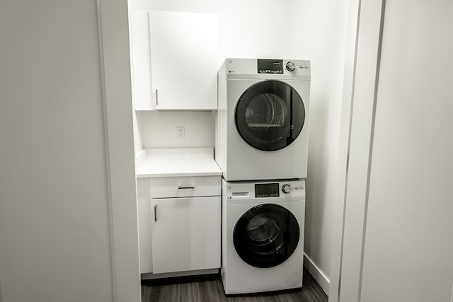 washroom featuring dark hardwood / wood-style flooring, cabinets, and stacked washer and dryer