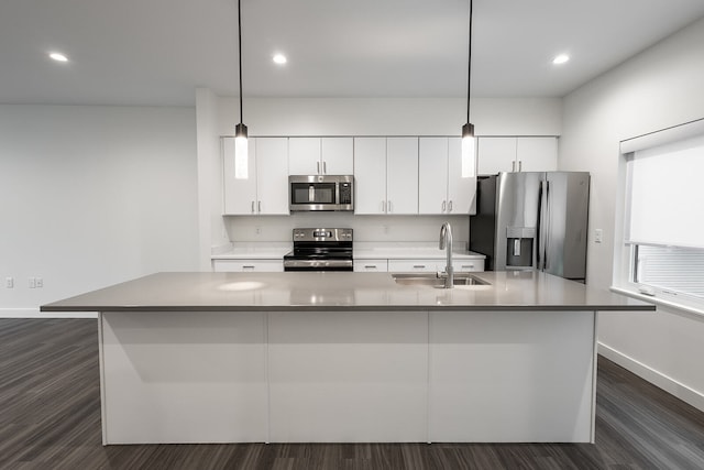 kitchen with sink, stainless steel appliances, dark wood-type flooring, and an island with sink