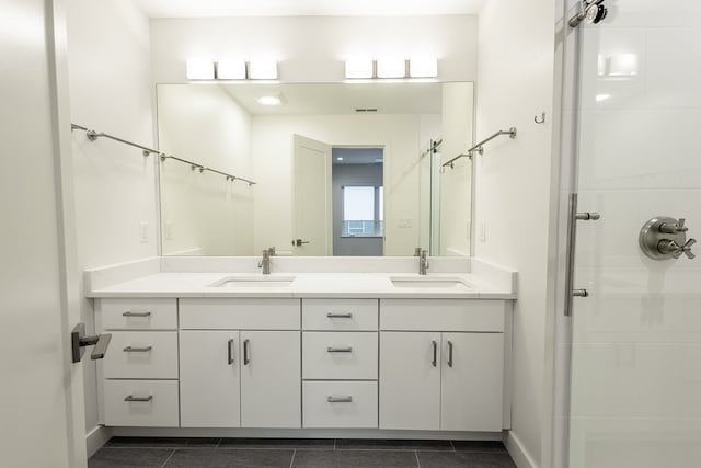 bathroom with a shower, double vanity, and tile flooring