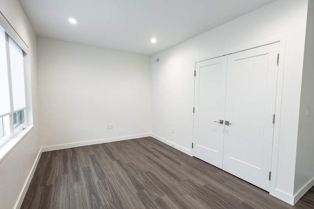 unfurnished bedroom featuring a closet and dark wood-type flooring