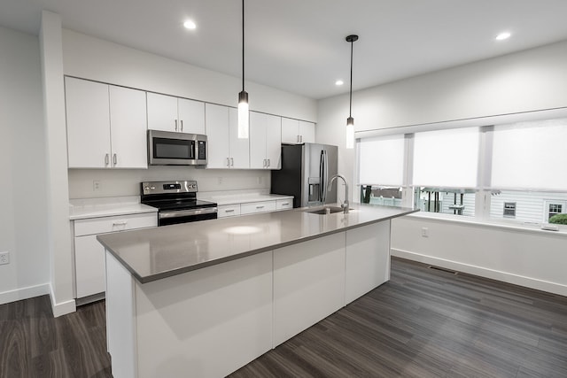 kitchen featuring an island with sink, stainless steel appliances, decorative light fixtures, white cabinets, and dark hardwood / wood-style flooring