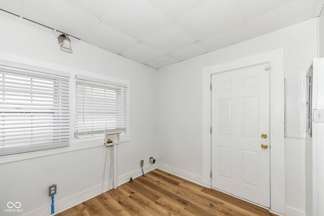 unfurnished room with hardwood / wood-style flooring and a drop ceiling