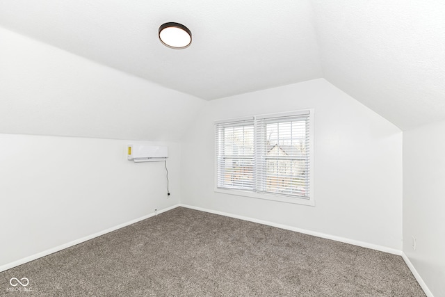 bonus room with carpet flooring, a textured ceiling, vaulted ceiling, and a wall mounted AC