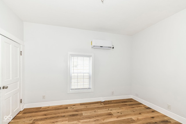 unfurnished room with wood-type flooring and a wall unit AC