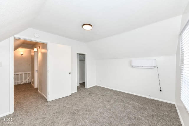 additional living space with an AC wall unit, carpet floors, and vaulted ceiling