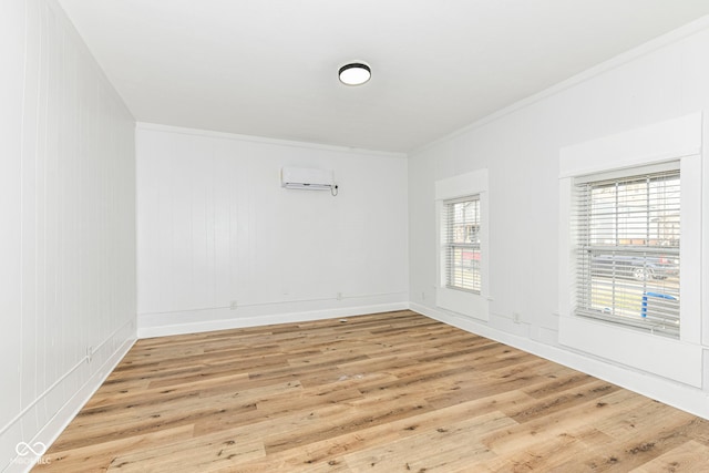 unfurnished room featuring light wood-type flooring, an AC wall unit, and crown molding