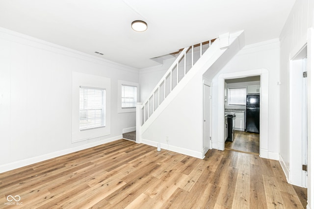 unfurnished living room featuring light hardwood / wood-style flooring and crown molding