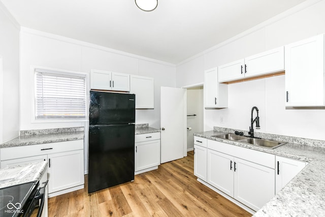 kitchen featuring black refrigerator, light wood-type flooring, white cabinetry, and sink