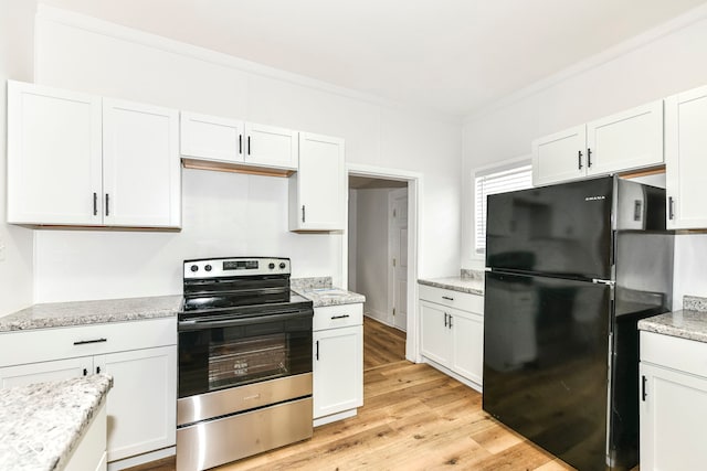 kitchen featuring white cabinets, black fridge, stainless steel electric range oven, and crown molding