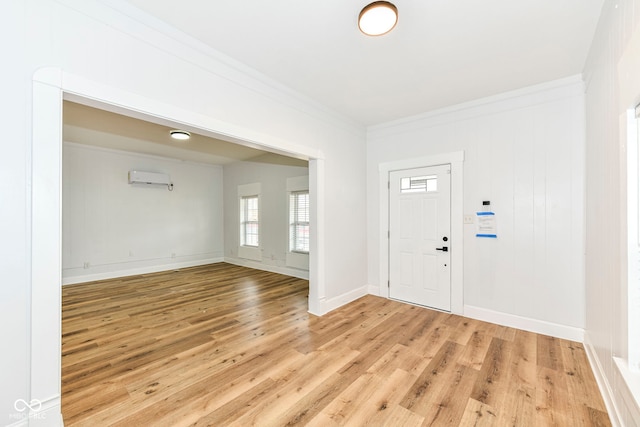 foyer with a wall mounted air conditioner, light hardwood / wood-style flooring, and ornamental molding