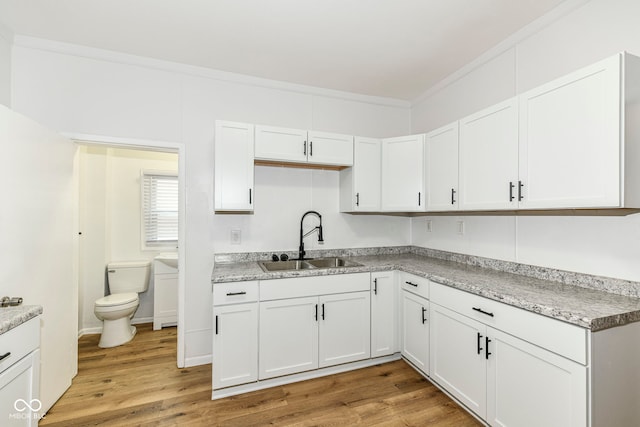 kitchen featuring white cabinets, light hardwood / wood-style floors, and sink