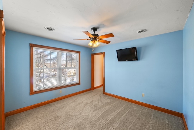 carpeted spare room featuring ceiling fan