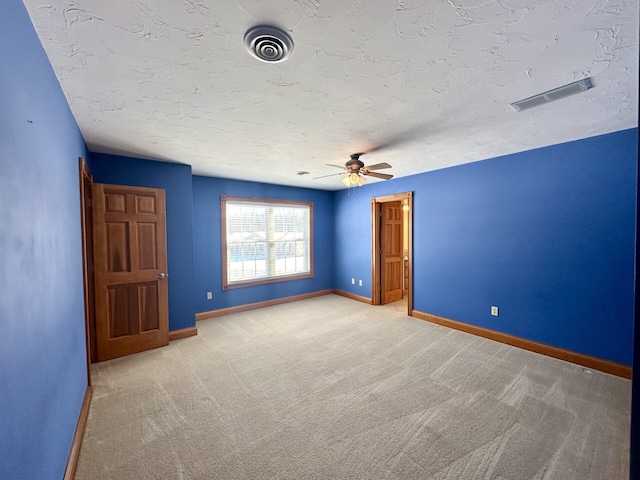 carpeted empty room featuring ceiling fan and a textured ceiling