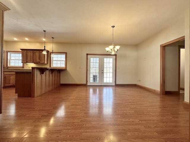 unfurnished living room featuring french doors, dark wood-type flooring, and a notable chandelier