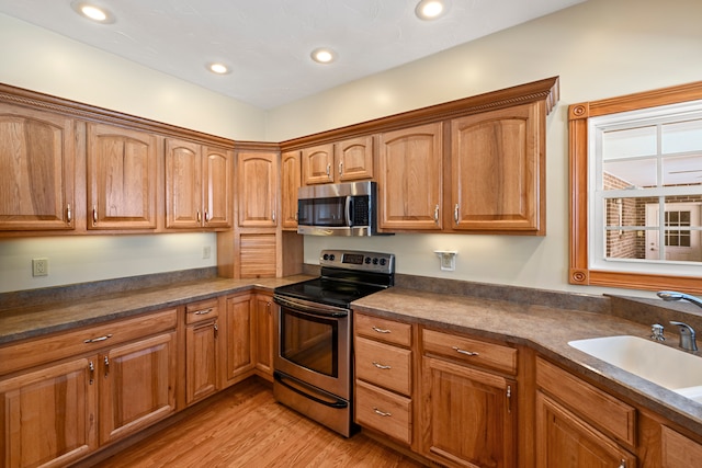 kitchen with appliances with stainless steel finishes, sink, and light wood-type flooring