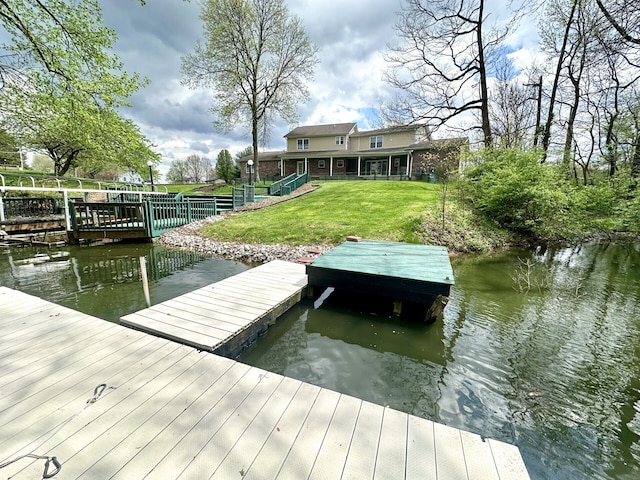 view of dock with a water view and a yard