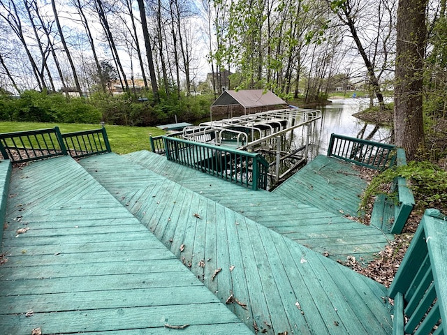 wooden deck with a water view and a lawn