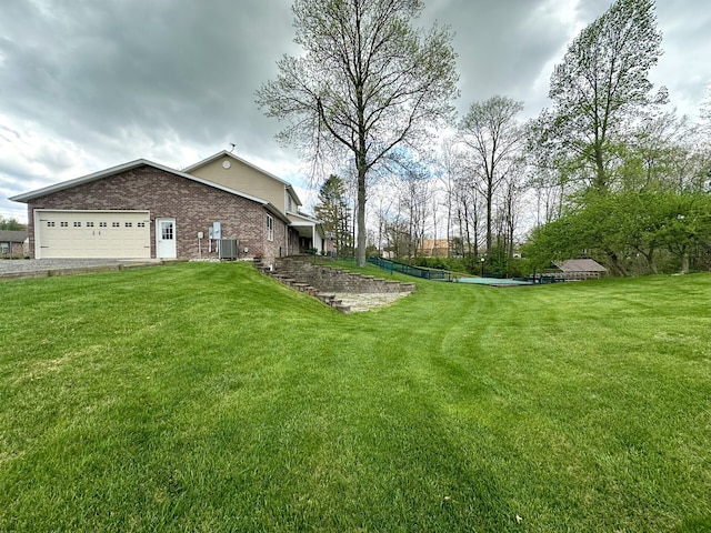 view of yard with central AC and a garage