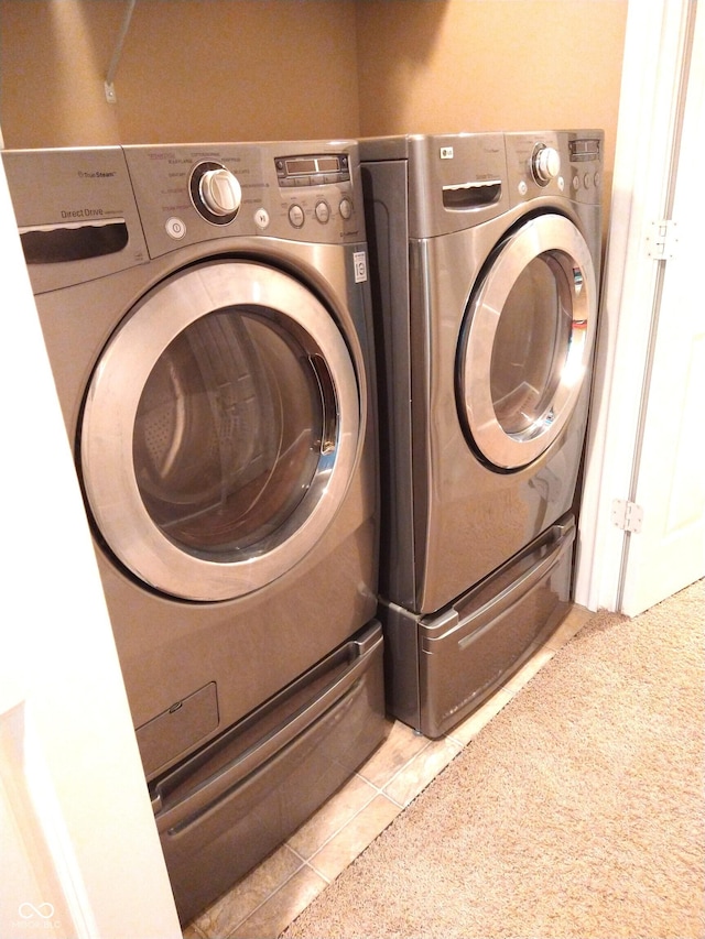 laundry area with light tile patterned flooring and washer and clothes dryer