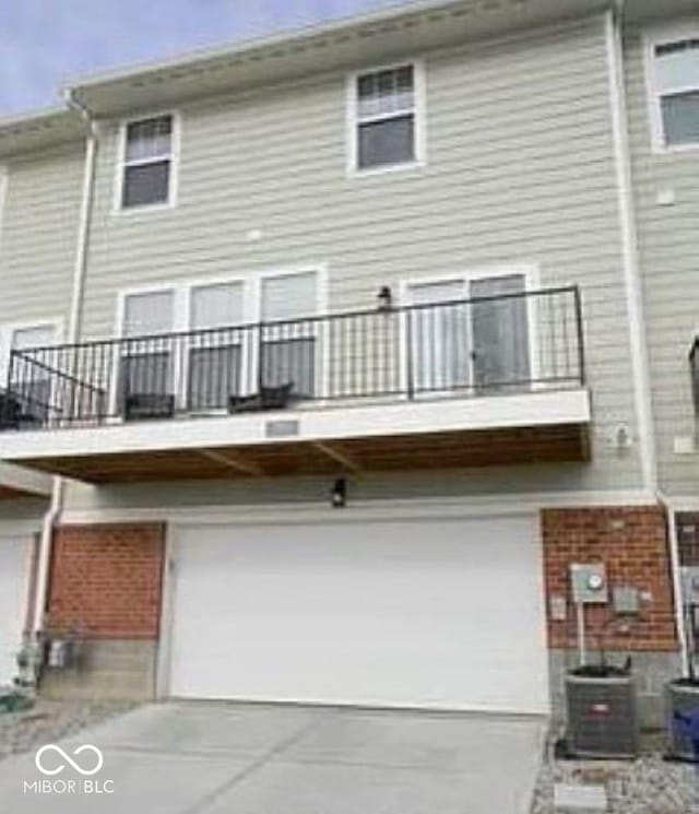 rear view of house featuring a garage, a balcony, and central air condition unit