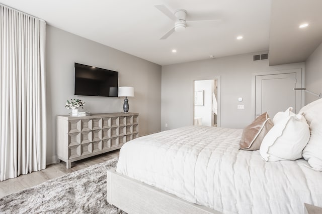 bedroom featuring ceiling fan, light hardwood / wood-style flooring, and connected bathroom