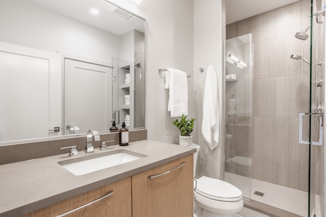 bathroom with toilet, large vanity, and an enclosed shower