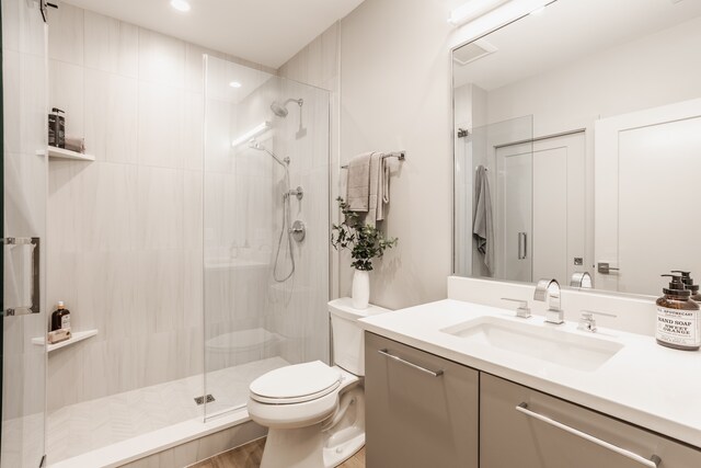 bathroom featuring toilet, a shower with shower door, and vanity