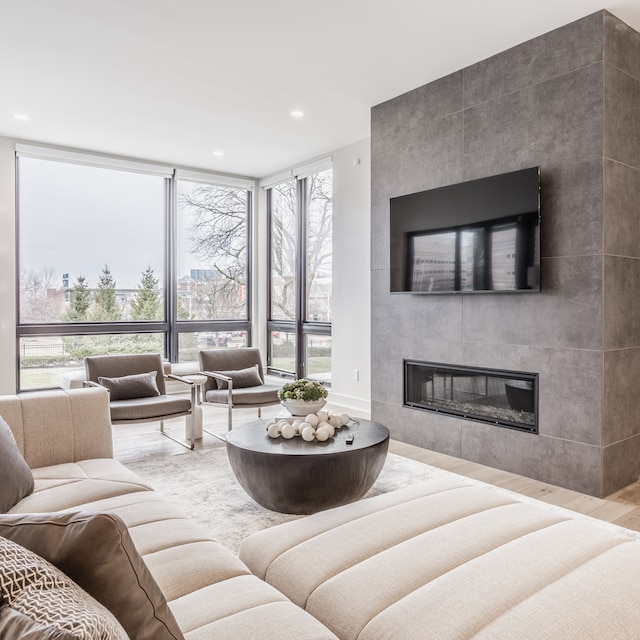 living room featuring a wall of windows, light wood-type flooring, and a large fireplace