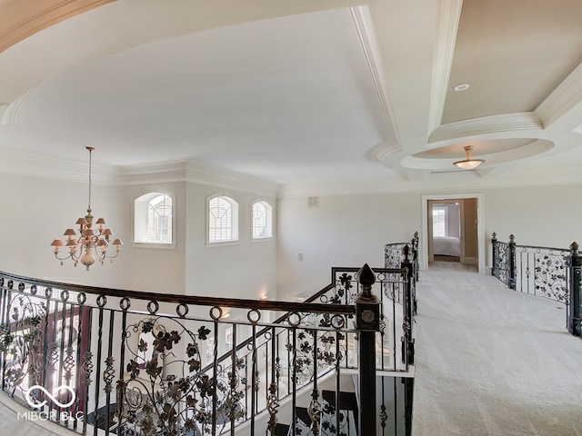 hallway with crown molding, light carpet, and a chandelier